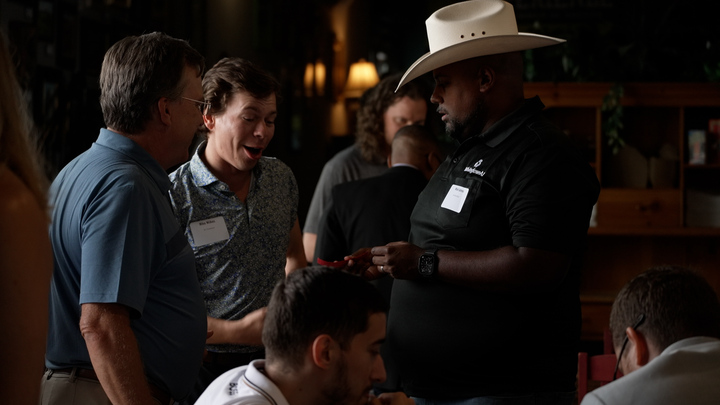 Three builders in conversation, cowboy hat in frame